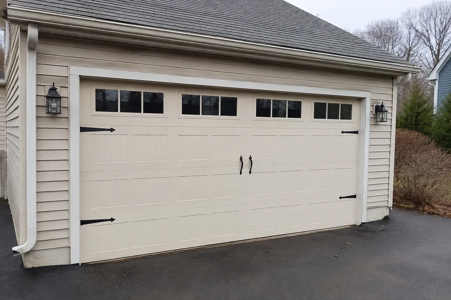 Cream carriage-house-style garage door with dark decorative hardware. — Carriage-House Garage Door Installation, Oro-Medonte