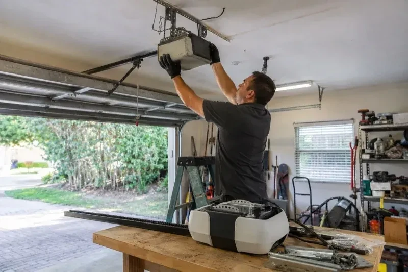 Person holding an overhead garage-door opener beside another opener and hardware on a workbench — Garage Door Opener Replacement, Oro-Medonte