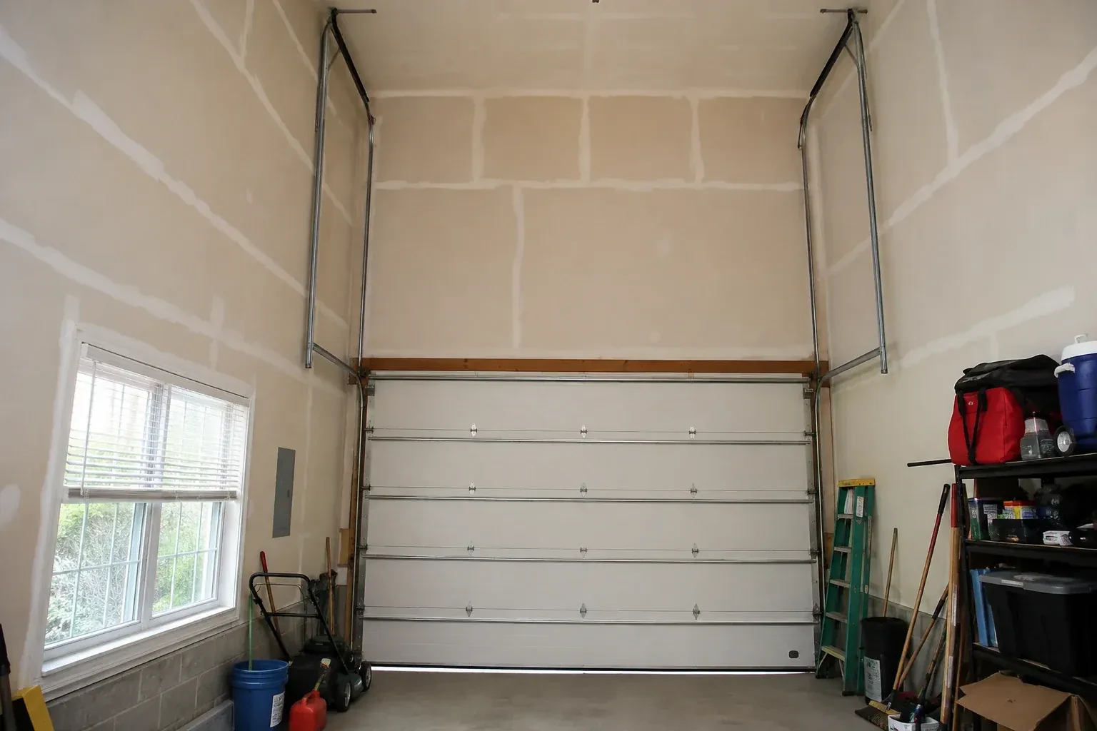 Tall garage interior with a sectional door and tracks extending into overhead space. — High-Lift Garage Door Conversion, Oro-Medonte